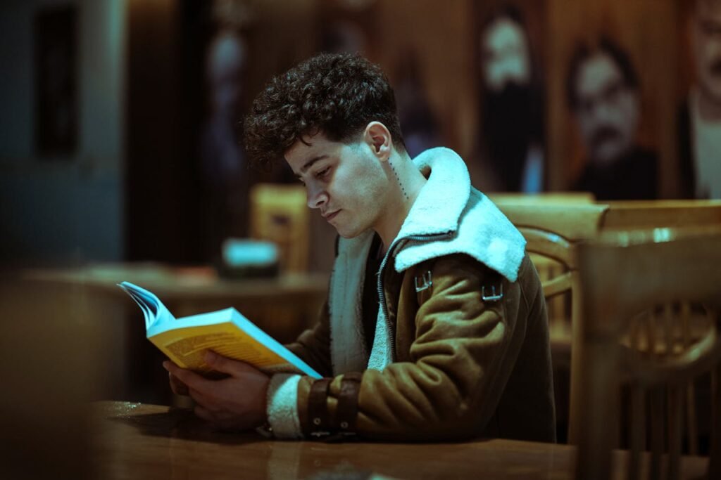A young man engrossed in a book at a cozy Tehran cafe, showcasing focus and leisure.