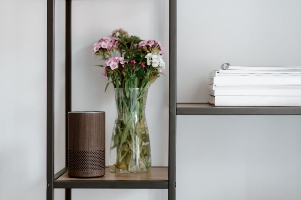 Elegant shelf setup with a smart speaker, vase of flowers, and stacked books for a minimalist touch.